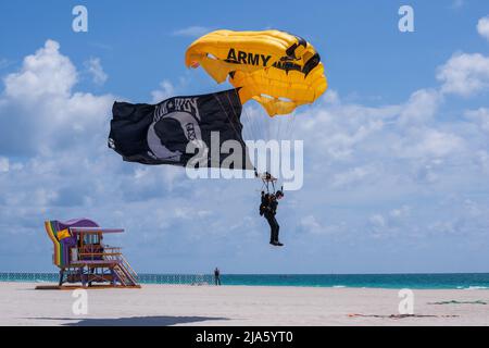SGT. Daniel McKeon della squadra di paracadute dell'esercito degli Stati Uniti atterra con la bandiera di POW su un salto di dimostrazione sopra alla spiaggia a Miami, Florida il 27 maggio, 2022. Il salto è in anticipo rispetto all'Hyundai Miami Air and Sea Show il 28 e 29 maggio. (STATI UNITI Esercito foto di Megan Hackett) Foto Stock