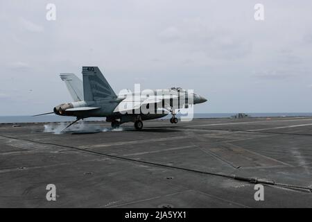 PHILIPPINE SEA (19 maggio 2022) un Super Hornet F/A-18E, assegnato ai "Vigilantes" di Strike Fighter Squadron (VFA) 151, fa un atterraggio arrestato sul ponte di volo a bordo del vettore aereo di classe Nimitz USS Abraham Lincoln (CVN 72). Abraham Lincoln Strike Group è in fase di implementazione pianificata nell'area delle operazioni della flotta USA 7th per migliorare l'interoperabilità attraverso alleanze e partnership, fungendo da forza di risposta pronta a supportare una regione indopacifica libera e aperta. (STATI UNITI Foto della Marina di Seaman Kassandra Alanis) Foto Stock