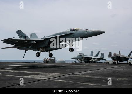 PHILIPPINE SEA (19 maggio 2022) un Super Hornet F/A-18E, assegnato ai 'Tophatters' di Strike Fighter Squadron (VFA) 14, si prepara a fare un atterraggio arrestato sul ponte di volo a bordo del vettore aereo di classe Nimitz USS Abraham Lincoln (CVN 72). Abraham Lincoln Strike Group è in fase di implementazione pianificata nell'area delle operazioni della flotta USA 7th per migliorare l'interoperabilità attraverso alleanze e partnership, fungendo da forza di risposta pronta a supportare una regione indopacifica libera e aperta. (STATI UNITI Foto della Marina di Seaman Kassandra Alanis) Foto Stock