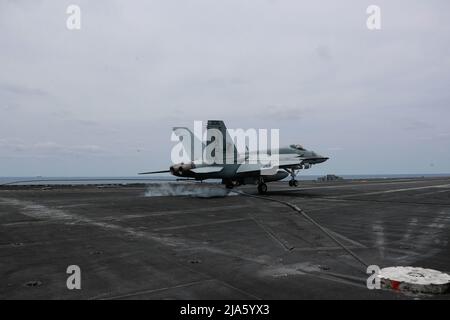 PHILIPPINE SEA (19 maggio 2022) un Super Hornet F/A-18E, assegnato ai 'Tophatters' di Strike Fighter Squadron (VFA) 14, fa un atterraggio arrestato sul ponte di volo a bordo del vettore aereo di classe Nimitz USS Abraham Lincoln (CVN 72). Abraham Lincoln Strike Group è in fase di implementazione pianificata nell'area delle operazioni della flotta USA 7th per migliorare l'interoperabilità attraverso alleanze e partnership, fungendo da forza di risposta pronta a supportare una regione indopacifica libera e aperta. (STATI UNITI Foto della Marina di Seaman Kassandra Alanis) Foto Stock