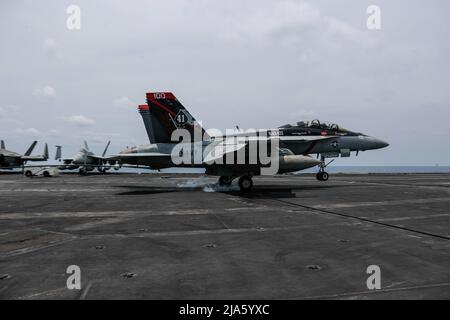 PHILIPPINE SEA (19 maggio 2022) un Super Hornet F/A-18F, assegnato al 'Black Aces' di Strike Fighter Squadron (VFA) 41, fa un atterraggio arrestato sul ponte di volo a bordo del vettore aereo di classe Nimitz USS Abraham Lincoln (CVN 72). Abraham Lincoln Strike Group è in fase di implementazione pianificata nell'area delle operazioni della flotta USA 7th per migliorare l'interoperabilità attraverso alleanze e partnership, fungendo da forza di risposta pronta a supportare una regione indopacifica libera e aperta. (STATI UNITI Foto della Marina di Seaman Kassandra Alanis) Foto Stock