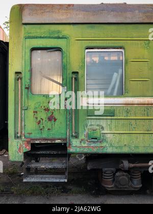 Primo piano di un vecchio vagone passeggeri sovietico arrugginito con vernice da peeling alle intemperie Foto Stock