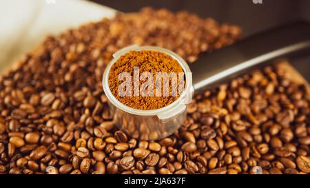 Caffè macinato in portafiltro su asse di legno con chicchi di caffè. Caffè appena macinato in portafiltro e fagioli tostati per la preparazione di fragranti d Foto Stock