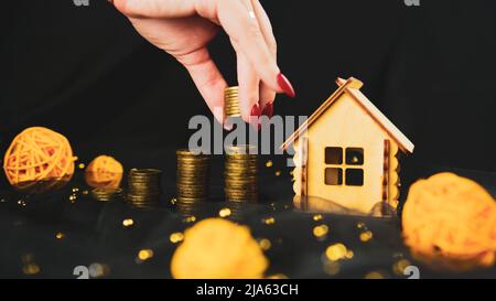 Donna che mette monete in pila per come risparmio per casa. Raccolto anonimo femmina raccolta monete in pila per gli investimenti immobiliari e risparmio di denaro per bu Foto Stock
