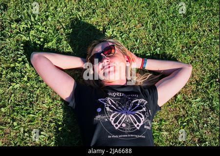 Bella donna bionda sdraiata nel prato Foto Stock