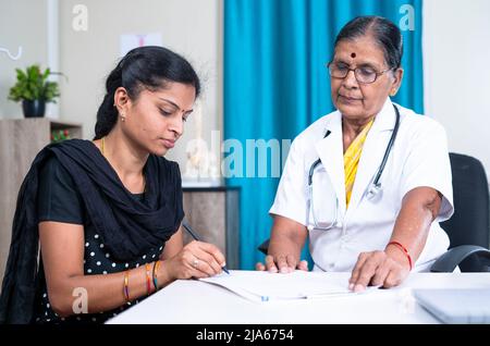 paziente femminile firma documenti di fronte al medico in ospedale - concetto di assicurazione sanitaria, e il consenso per la politica Foto Stock
