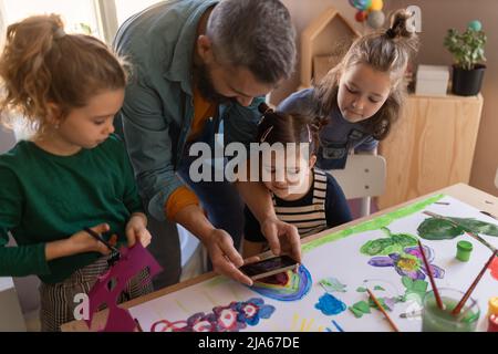 Gruppo di bambini che lavorano al progetto con l'insegnante durante le lezioni di arte creativa e artigianato a scuola. Foto Stock