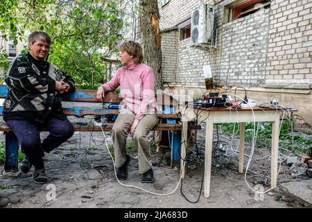 Verkhnokmayanske, Ucraina. 27th maggio 2022. Persone che caricano i loro telefoni. Verkhnokmayanske è una piccola città della regione di Donetsk. La città soffre di una carenza di cibo e medicinali, gas, acqua e interruzione dell'elettricità. Di conseguenza, la prima linea si avvicina ogni giorno alla città e la maggior parte dei civili fugge. Credit: SOPA Images Limited/Alamy Live News Foto Stock