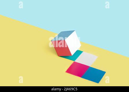 Il cubo multicolore lascia segni su uno sfondo giallo e blu. Astratto concetto minimo. Layout isometrico con spazio di copia. Forma geometrica Foto Stock