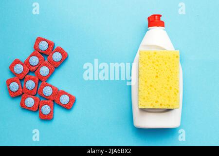 capsule per lavastoviglie, detersivi per lavastoviglie liquido e spugne su fondo blu. lavastoviglie vs lavamani concetto. che è meglio. piatto. Foto Stock