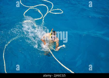 L'uomo africano è impegnato nello snorkeling. Un uomo in maschera e pinne nuota sul mare. Vista dall'alto. Hurghada, Egitto - Marzo 2022 Foto Stock