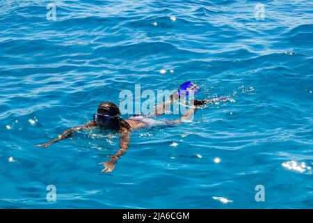 L'uomo africano è impegnato nello snorkeling. Un uomo in maschera e pinne nuota sul mare. Vista dall'alto. Hurghada, Egitto - Marzo 2022 Foto Stock