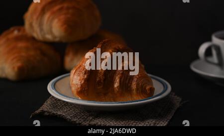 Croissant appena sfornati e una tazza di caffè su un tavolo di legno. Levitation, concetto di caffè di prodotti da forno del pane Foto Stock