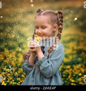 Ritratto di un ragazzo carino villaggio ragazza con fiore su un campo di fiori. Un bambino in un prato fiorente. Foto Stock