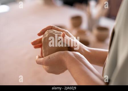 primo piano della mano del vasaio femminile. ceramista professionale al lavoro usando gli attrezzi di preparazione della tazza fatti a mano in studio, fuoco selettivo. la formazione di fatto a mano Foto Stock