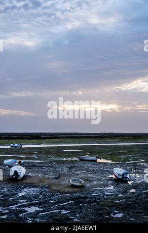 La bassa marea sulle paludi della città di Faro lascia diverse piccole barche da pesca bloccate. Foto Stock