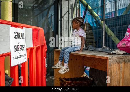 Bambino seduto al di fuori della banca alimentare per le famiglie che soffrono di difficoltà finanziarie. Lewisham Donation Hub, Londra , Inghilterra . Foto Stock