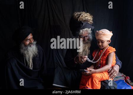 Prayagraj, Uttar Pradesh, India. 22nd Jan 2019. Due uomini santi si prendono cura di un bambino sadhu nella loro tenda al festival Kumbh Mela. Ogni dodici anni, milioni di devoti indù iniziano un massiccio pellegrinaggio verso il più sacro dei festival indiani: Il Kumbha Mela, che si svolge a Prayagraj, un luogo considerato particolarmente propizio perché è alla confluenza del Gange, Yamuna e il mitico Saraswati. Si stima che nel 2019 120 milioni di persone hanno partecipato alla sacra recinzione nel corso di un mese e mezzo. Questi numeri, equivalenti alla popolazione totale del Giappone, a Foto Stock