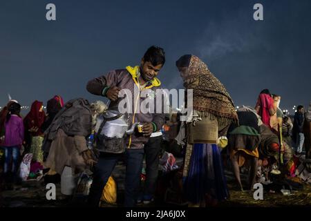 Prayagraj, Uttar Pradesh, India. 1st Feb 2019. Un venditore di chai dà un tè ad un venditore di fiori sulle rive del fiume Gange durante il festival di Kumbh Mela. Ogni dodici anni, milioni di devoti indù iniziano un massiccio pellegrinaggio verso il più sacro dei festival indiani: Il Kumbha Mela, che si svolge a Prayagraj, un luogo considerato particolarmente propizio perché è alla confluenza del Gange, Yamuna e il mitico Saraswati. Si stima che nel 2019 120 milioni di persone hanno partecipato alla sacra recinzione nel corso di un mese e mezzo. Questi numeri, equivalenti al totale p Foto Stock