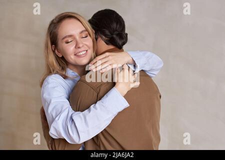 Ritratto orizzontale medio di felice bionda donna innamorata abbracciando il suo ragazzo con gli occhi chiusi Foto Stock