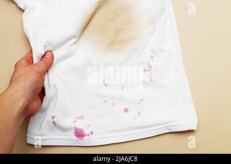 Macchie sporche su una T-shirt bianca da bacche e bere su sfondo marrone. Foto Stock