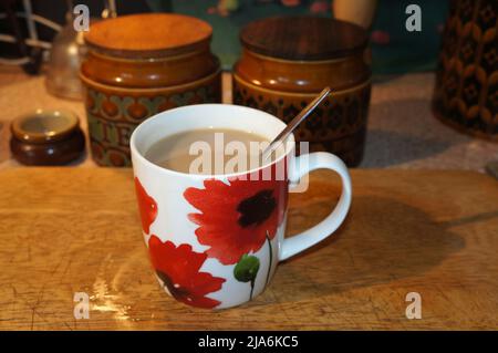 Una tazza di tè con fiori su tavola di legno Foto Stock