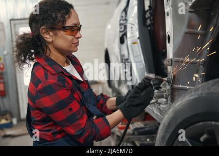 Meccanico donna che ripara l'auto in garage Foto Stock