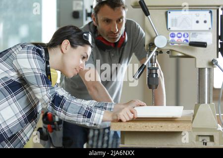 Giovani tecnici lavorando sul montante macchina perforatrice in officina Foto Stock