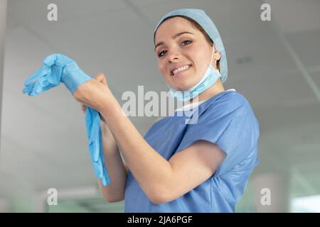 medico donna che indossa guanti chirurgici sterilizzati blu Foto Stock