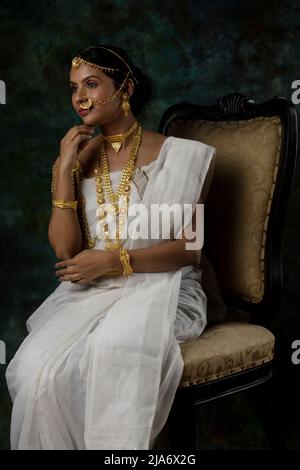 Modella femminile indiana che indossa un sari bianco e gioielli in oro con un look tradizionale bengalese o un look binodini, un modello sari, un'etnia indiana Foto Stock