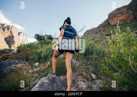 Vista posteriore della donna che cammina sul sentiero di montagna. Donna escursionista in abbigliamento sportivo facendo escursioni in terreno selvatico. Foto Stock