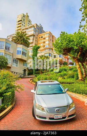 Auto che guida lungo Lombard Street con mattoni rossi strada tortuosa e case Foto Stock