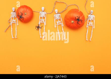 Zucca di Halloween con scheletri e ragni neri su sfondo arancione. Foto Stock