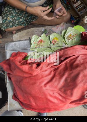 Foglie di Betel verde o mitha paan essendo preparato con ingredienti come areka Nut o supari e altri condimenti in un negozio per la vendita in india. Un famoso p Foto Stock