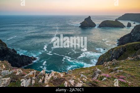 La costa della Cornovaglia, Inghilterra. Una serata estiva e il cielo splendente mentre il sole tramonta sulla spettacolare e frastagliata costa Foto Stock