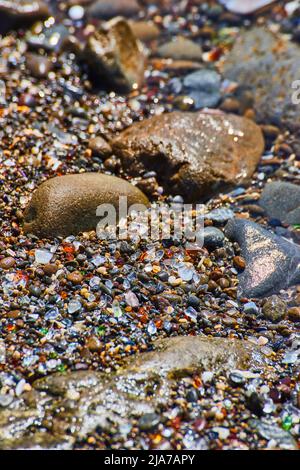 Rocce da spiaggia con pezzi di vetro che riempiono tutti gli spazi vuoti Foto Stock