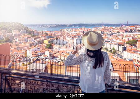 Una donna turistica in un viaggio turistico si affaccia sul colorato paesaggio urbano di Lisbona Foto Stock