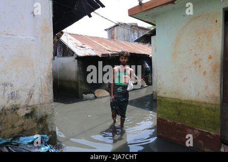 Sylhet, Bangladesh. 24th maggio 2022. Giovane uomo che attraversa acqua sporca con cibo per la sua famiglia a Sylhet, Bangladesh. L'acqua flood flash entra nelle case della città di Sylhet a causa dell'aumento del livello dell'acqua nei fiumi Surma e Kushiyara. (Credit Image: © Pinu Rahman/Pacific Press via ZUMA Press Wire) Foto Stock