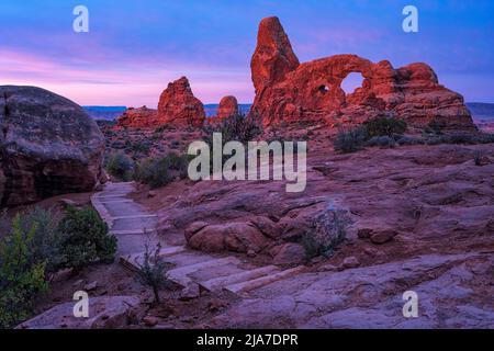 Il Turret Arch si illumina all'alba nel parco nazionale di Arches, vicino a Moab, Utah Foto Stock