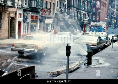 Aperto idrante antincendio e vecchi parchimetri nel centro di New York, agosto 1977 Foto Stock