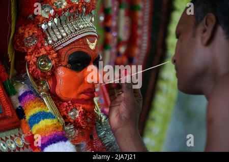 Theyyam è una famosa forma d'arte rituale in kerala con il volto dipinto utilizzando colori organici e l'uso di strumenti musicali come Chenda, Elathalam, , Kurumkuzal Foto Stock