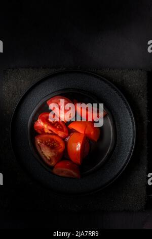 spicchi di pomodoro su un piatto nero Foto Stock