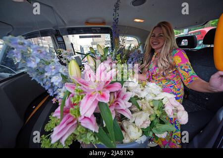 Visitatore Sarah Hart in un taxi caricato con i suoi acquisti di fiori - acquistato dalla suite Queen Mary durante la vendita dello stabilimento l'ultimo giorno del RHS Chelsea Flower Show, E per essere usato per il suo matrimonio a Richmond mercoledì 1 giugno - al Royal Hospital Chelsea, Londra. Data foto: Sabato 28 maggio 2022. Foto Stock