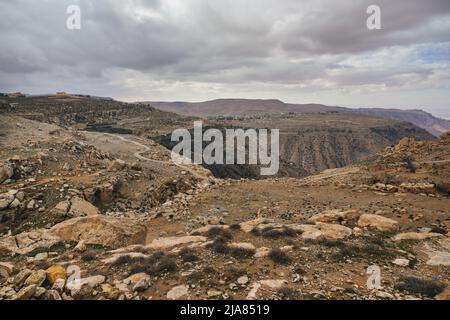 Ampio panorama della riserva della biosfera di Dana in Giordania, nuvole grigie sovrastanti su un grande canyon Foto Stock