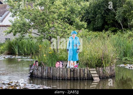 REGNO UNITO. 28th maggio 2022. I Prankers hanno preso di mira il Villaggio di Rottingdean Pond in Sussex facendo una mostra per le celebrazioni giubilari. I hanno messo un taglio di carboard della regina con un Corgi e le facce della famiglia reale intorno ad un'isola nel mezzo dello stagno per rappresentare il balcone al palazzo di Buckingham. Hanno messo la faccia di Andrew di prezzo via da tutto e sull'altro lato dell'isola ci è il principe Harry e Megan accreditamento: @Dmoonuk/Alamy Live News Foto Stock