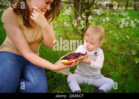 madre e figlia mangiano il pane della marmellata in una sorgente di picnic Foto Stock