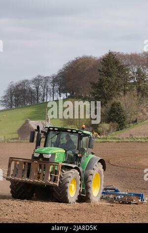 Un trattore John Deere 6175R che tira uno scarificatore su un campo arato in preparazione alla semina di un raccolto di cereali Foto Stock