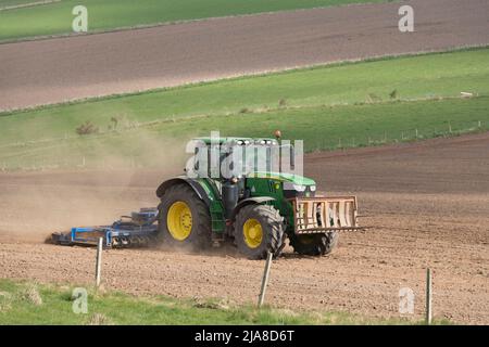 Un trattore John Deere verde che tira uno scarificatore su un campo arato su terreni agricoli nell'Aberdeenshire Foto Stock