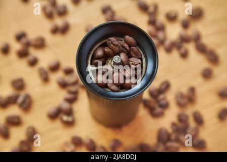 Macinacaffè manuale per macinare chicchi di caffè con chicchi di caffè e caffè macinato su sfondo di legno Foto Stock
