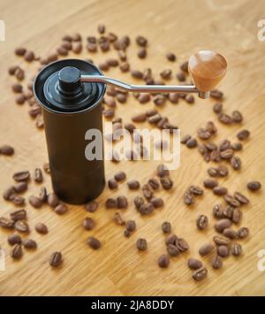 Macinacaffè manuale per macinare chicchi di caffè con chicchi di caffè e caffè macinato su sfondo di legno Foto Stock